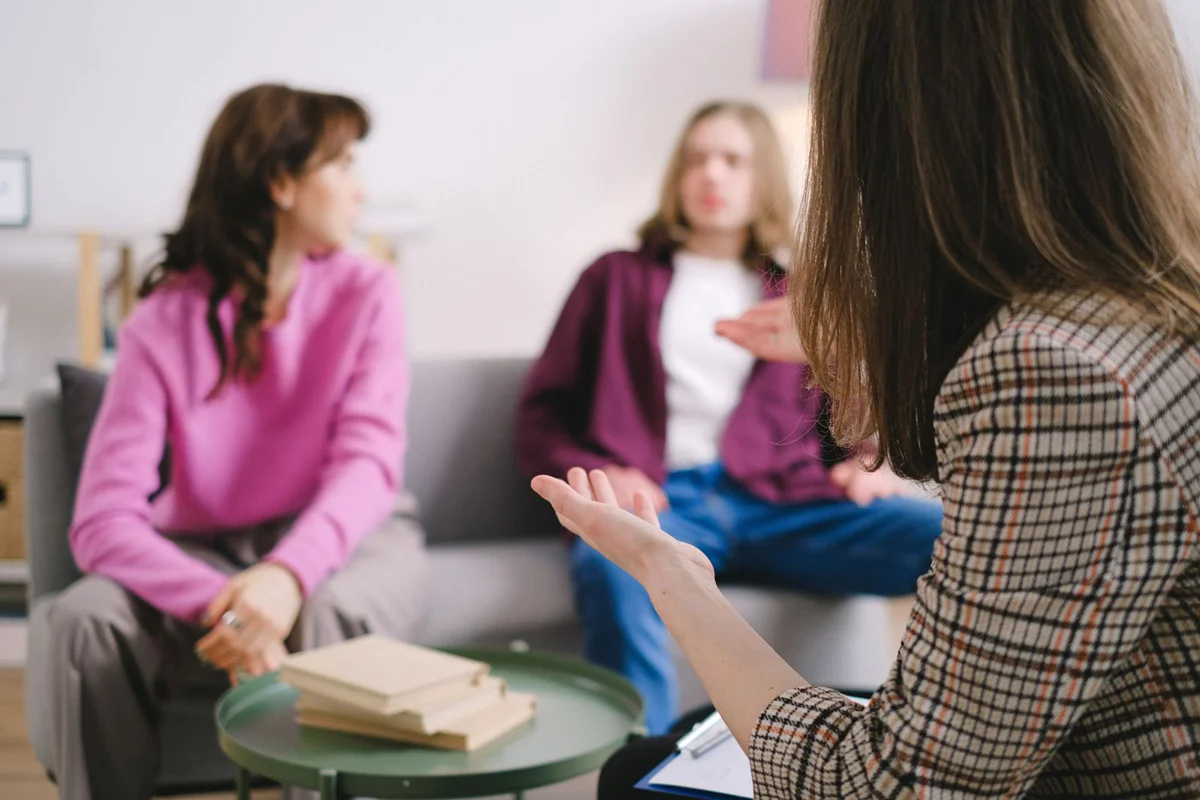 Un petit groupe d'adultes en conversation dans un salon chaleureux.